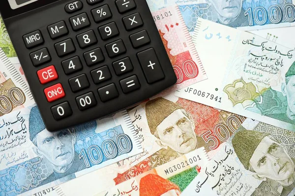Pakistan banknotları ve hesap makinesi. Pakistan 'ın mevcut para ve hesap makinesi büyük miktarda masada yatıyor. Pakistan 'da vergi ve para sayımı kavramı
