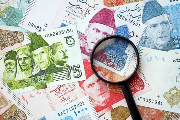 Pakistan banknotları ve büyüteç. Pakistan 'ın mevcut para ve büyüteç faturaları büyük miktarda masanın üzerinde duruyor. Pakistan 'da mali izleme ve vergilendirme kavramı