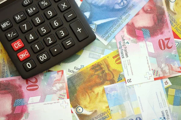 İsviçre frangı banknotları ve hesap makinesi. Mevcut frank para faturaları ve calc büyük miktarda masada yatıyor. İsviçre 'de vergilendirme ve para konsepti