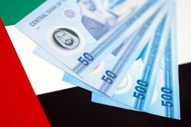 Birleşik Arap Emirlikleri kara para birimi banknotları bayrağa yakın duruyor. İş ve yatırım kavramı
