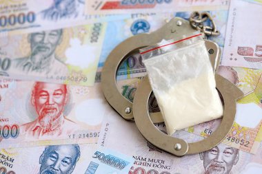 Vietnam dong para birimi faturaları ve kelepçeli kokain paketi. Uyuşturucu suçları kavramı