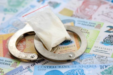 Nijerya naira para birimi faturaları ve kelepçeli kokain paketi. Uyuşturucu suçları kavramı