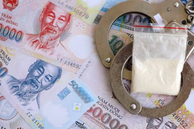 Vietnam dong para birimi faturaları ve kelepçeli kokain paketi. Uyuşturucu suçları kavramı