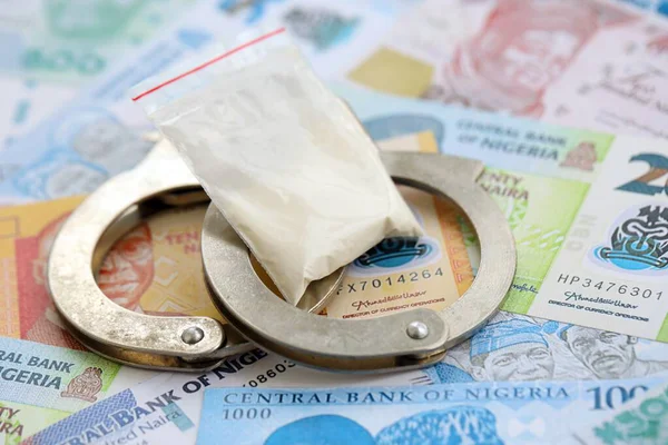 Nijerya naira para birimi faturaları ve kelepçeli kokain paketi. Uyuşturucu suçları kavramı