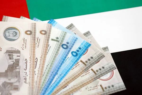Birleşik Arap Emirlikleri kara para birimi banknotları bayrağa yakın duruyor. İş ve yatırım kavramı