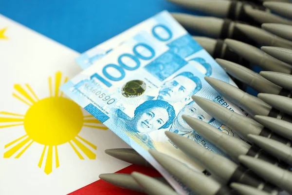 Filipinler para birimi banknotları ve bayraklar üzerinde tüfek mermileri. Savaş ve silah satışı kavramı