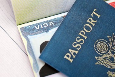 Açık pasaport sayfasında ABD vizesi ve arka planda ABD pasaport kapağı