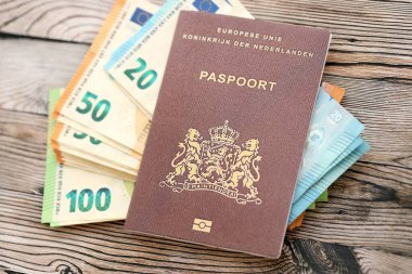Hollanda pasaportu, ahşap arka planda Avro para banknotlarıyla kaplıdır. Avrupa konseptinde nakit ve ödemeler