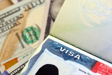 ABD vizesi ücreti 250 dolar, pasaport için ABD vizesi ve arka planda Amerikan para faturaları.