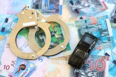 Kuveyt dinarı para birimi faturaları ve kelepçeli oyuncak araba. Araba kazası kavramı.