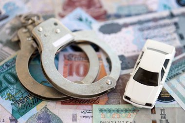 Mısır para birimi banknotları ve kelepçeli oyuncak araba. Araba kazası kavramı.