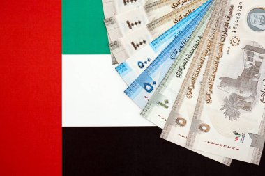 Birleşik Arap Emirlikleri kara para birimi banknotları bayrağa yakın duruyor. İş ve yatırım kavramı