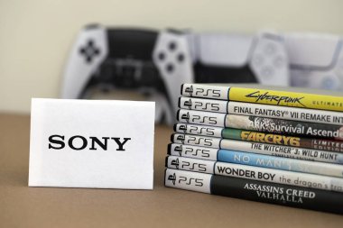 KYIV, UKRAINE - SEPTEMBER 17, 2025 Stack of PS5 videogame disc boxes and modern dualsense edge gamepad. SONY logo in front close up