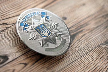 KYIV, UKRAINE - SEPTEMBER 17, 2025 Ukrainian Police badge on brown wooden table surface close up
