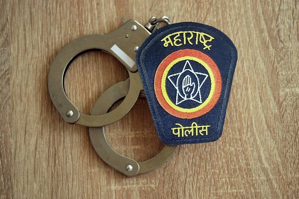 KYIV, UKRAINE - SEPTEMBER 17, 2025 India Police badge with handcuffs on wooden table close up