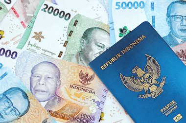 KYIV, UKRAINE - JANUARY 27, 2024 Indonesia passport and many indonesian rupiah currency money bills close up