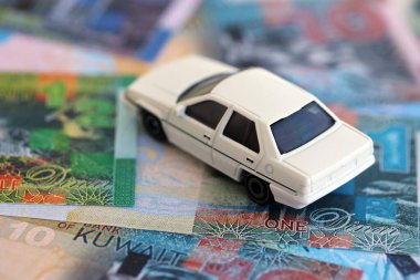 Kuveyt dinarı para ve oyuncak araba faturaları. Araba sahibi olma kavramı.