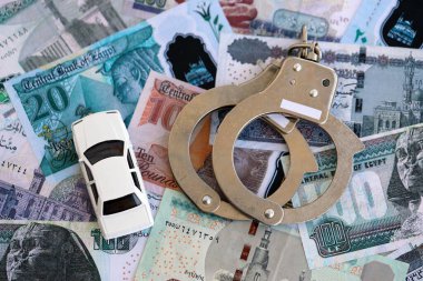 Mısır para birimi banknotları ve kelepçeli oyuncak araba. Araba kazası kavramı.