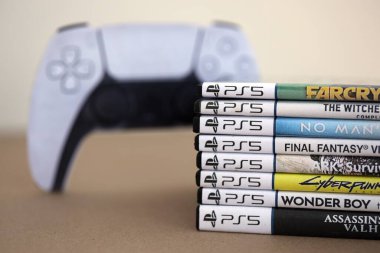 KYIV, UKRAINE - 17 Eylül 2025 PS5 video oyun disk kutuları ve modern dualsense kenar oyun sahası yakınlaşması