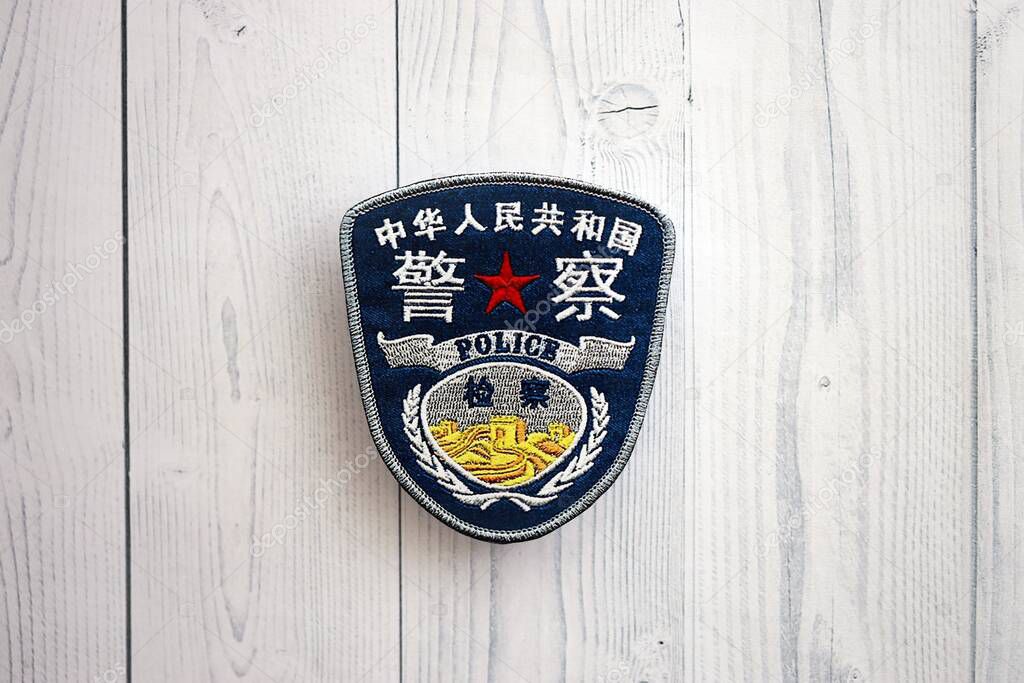 KYIV, UKRAINE - SEPTEMBER 17, 2025 Chinese Police badge on white wooden table surface close up