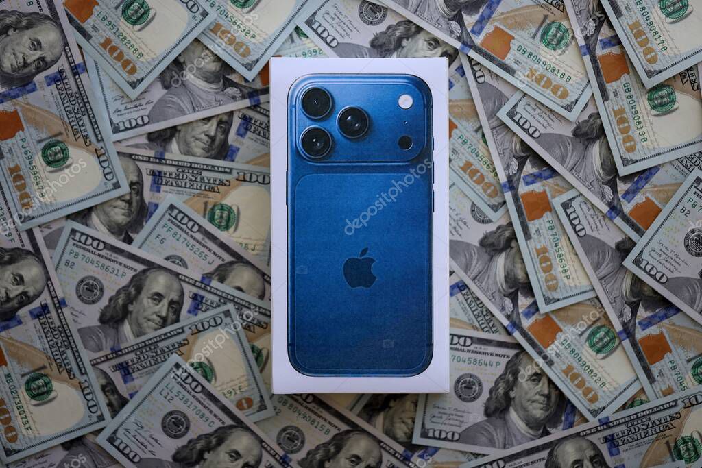 KYIV, UKRAINE - SEPTEMBER 21, 2025 Apple iPhone 17 Pro Max Deep Blue box on big amount of US dollar bills close up