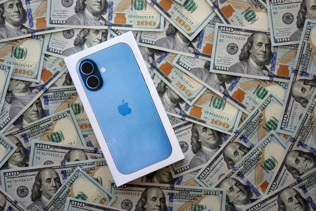KYIV, UKRAINE - SEPTEMBER 21, 2025 Apple iPhone 17 Mist Blue box on big amount of US dollar bills close up