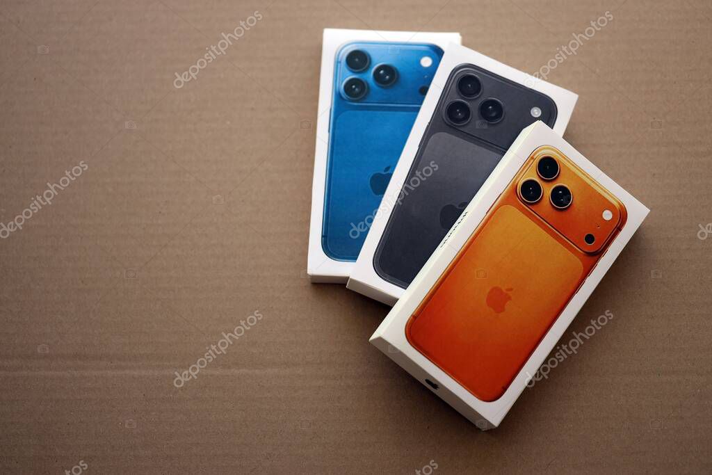 KYIV, UKRAINE - SEPTEMBER 21, 2025 Apple iPhone 17 Pro Max Cosmic Orange box and other iPhone model box on cardboard surface close up