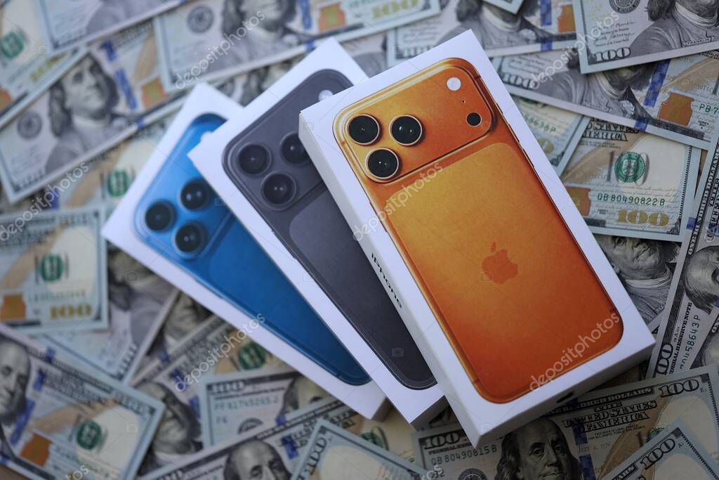 KYIV, UKRAINE - SEPTEMBER 21, 2025 Apple iPhone 17 Pro Max Cosmic Orange box on big amount of US dollar bills close up