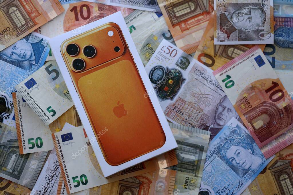 KYIV, UKRAINE - SEPTEMBER 21, 2025 Apple iPhone 17 Pro Max Cosmic Orange box on big amount of GB pounds and euro bills close up
