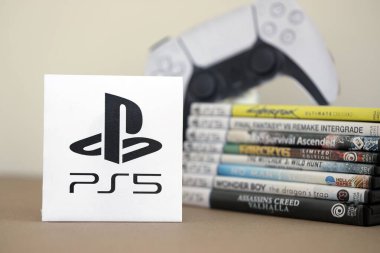 KYIV, UKRAINE - 17 Eylül 2025 PS5 video oyun diski kutuları ve modern dualsense kenar oyun sahası. Ön tarafta PS5 logosu var.