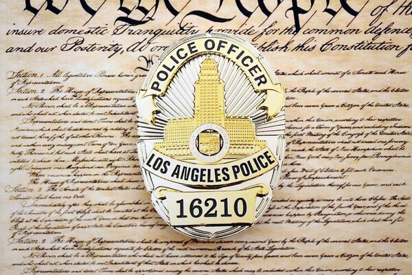 KYIV, UKRAINE - SEPTEMBER 17, 2025 US LAPD Police officer badge on first page of US Constitution replica close up