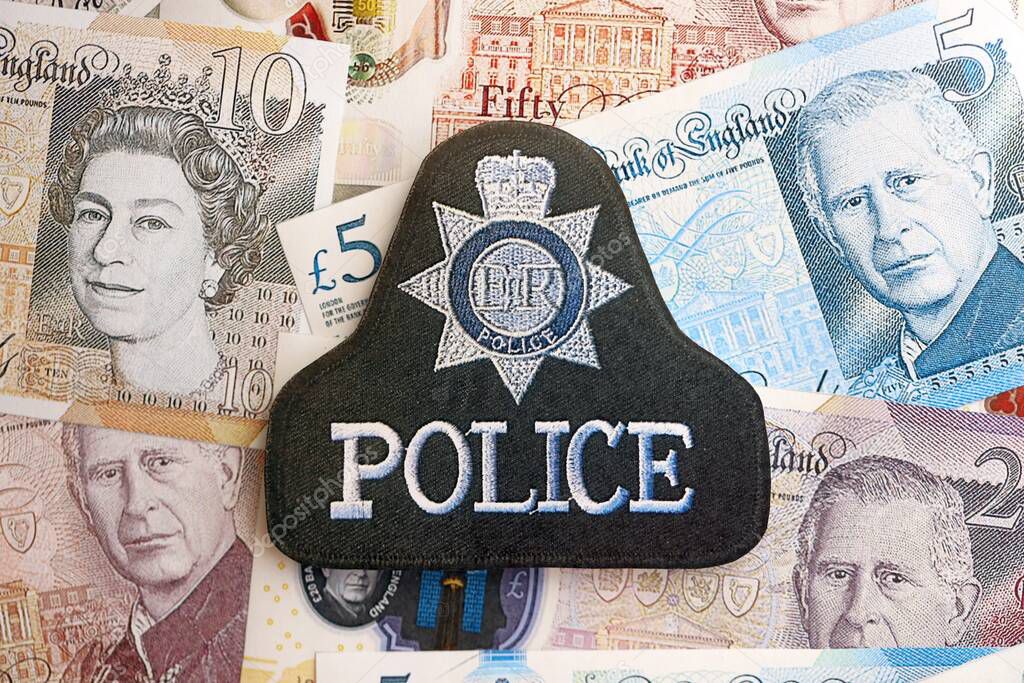 KYIV, UKRAINE - SEPTEMBER 17, 2025 United Kingdom Police badge on British pound money bills close up