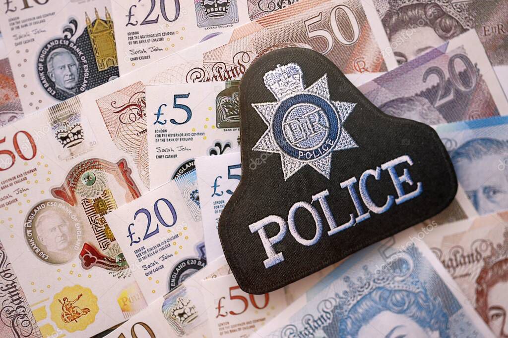 KYIV, UKRAINE - SEPTEMBER 17, 2025 United Kingdom Police badge on British pound money bills close up