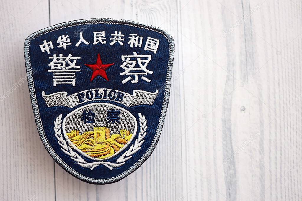 KYIV, UKRAINE - SEPTEMBER 17, 2025 Chinese Police badge on white wooden table surface close up