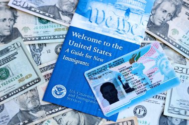 Kalıcı ikamet eden yeşil kart ve yeni göçmenler için rehber birçok dolarlık banknotların üzerinde yatar.