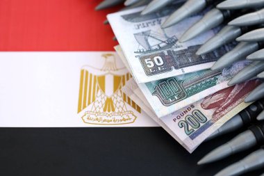 Mısır para birimi banknotları ve bayraklar üzerinde tüfek mermileri. Savaş ve silah satışı kavramı