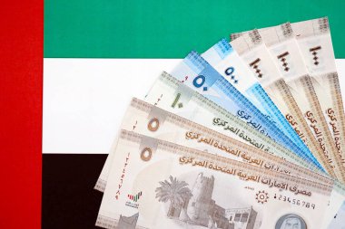 Birleşik Arap Emirlikleri kara para birimi banknotları bayrağa yakın duruyor. İş ve yatırım kavramı