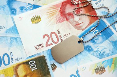 İsrail Yeni Şekelleri 'nin banknotları ve askeri simgesi. İsrail 'in mevcut para faturaları ve künyeleri büyük miktarda masada yatıyor. İsrail 'de askerlik kavramı