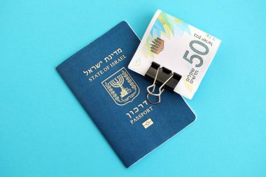 Israel New Shekels banknotları ve mavi arka planda pasaport. İsrail 'in şu anki para banknotları büyük oranda mavi üzerine yatar. İsrail 'de finans ve nakit kavramı