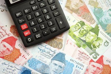 Pakistan banknotları ve hesap makinesi. Pakistan 'ın mevcut para ve hesap makinesi büyük miktarda masada yatıyor. Pakistan 'da vergi ve para sayımı kavramı