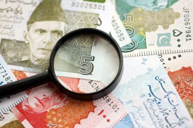 Pakistan banknotları ve büyüteç. Pakistan 'ın mevcut para ve büyüteç faturaları büyük miktarda masanın üzerinde duruyor. Pakistan 'da mali izleme ve vergilendirme kavramı