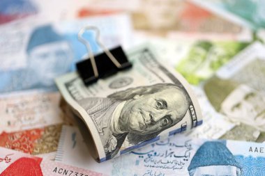 Amerikan dolarlarının rulosu Pakistan 'daki büyük miktardaki banknotların üzerinde yatıyor. Amerikan para demeti Pakistan 'ın para banknotlarında yatıyor. Pakistan 'da ekonomi ve döviz kuru kavramı