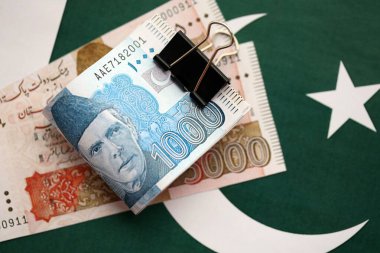 Pakistan bayrağı üzerinde Pakistan banknotları. Pakistan 'ın mevcut para faturaları büyük miktarlarda pankartta yatıyor. Pakistan 'da ekonomi ve ticaret kavramı