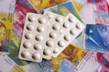 İsviçre frangı ve ilaç hapları. Mevcut para ve uyuşturucu banknotları büyük miktarda masada yatıyor. İsviçre 'de ilaç ve eczane kavramı