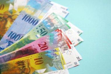 Mavi arka planda İsviçre frangı banknotları. Mevcut frank para faturaları büyük miktarda masada yatıyor. İsviçre 'de iş ve yatırım kavramı