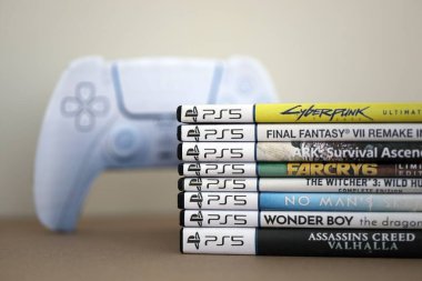 KYIV, UKRAINE - 17 Eylül 2025 PS5 video oyun disk kutuları ve modern dualsense kenar oyun sahası yakınlaşması