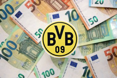 KYIV, UKRAINE - 23 Şubat 2025 Borussia Dortmund futbol kulübü rozeti büyük miktarda EURO para banknotlarının üzerinde yatıyor