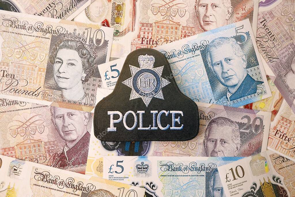 KYIV, UKRAINE - SEPTEMBER 17, 2025 United Kingdom Police badge on British pound money bills close up