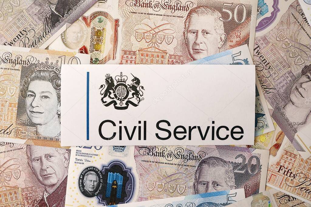 KYIV, UKRAINE - SEPTEMBER 17, 2025 UK Civil Service logotype sticker lies on British pounds money bills close up