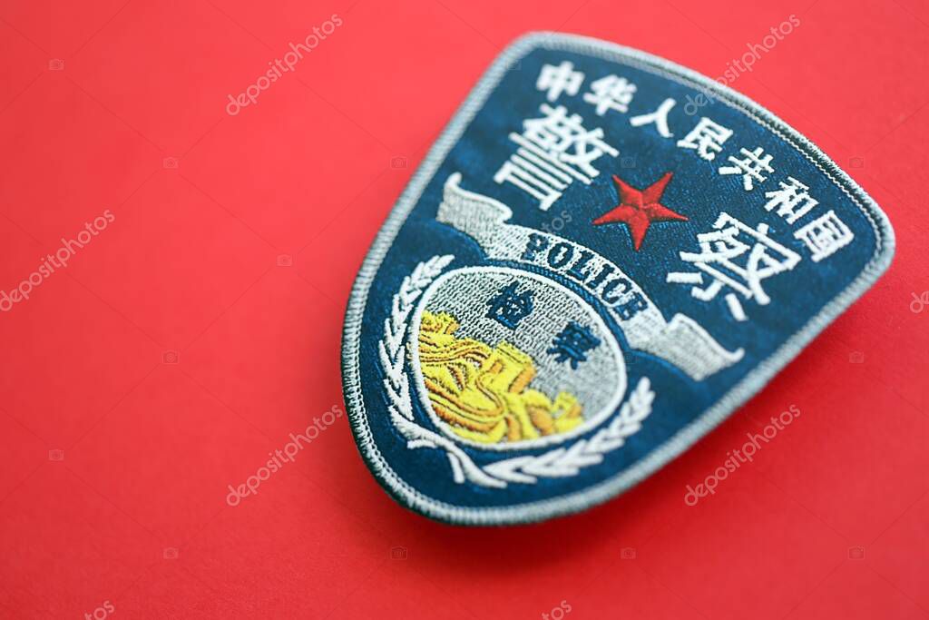 KYIV, UKRAINE - SEPTEMBER 17, 2025 Chinese Police badge on national flag surface close up